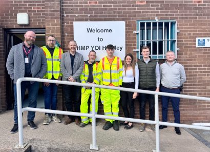 HW Martin Team of people stand in front of the HMP Hindley Sign