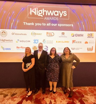 Four people pose on stage in front of a sign for the Highways Awards 2025